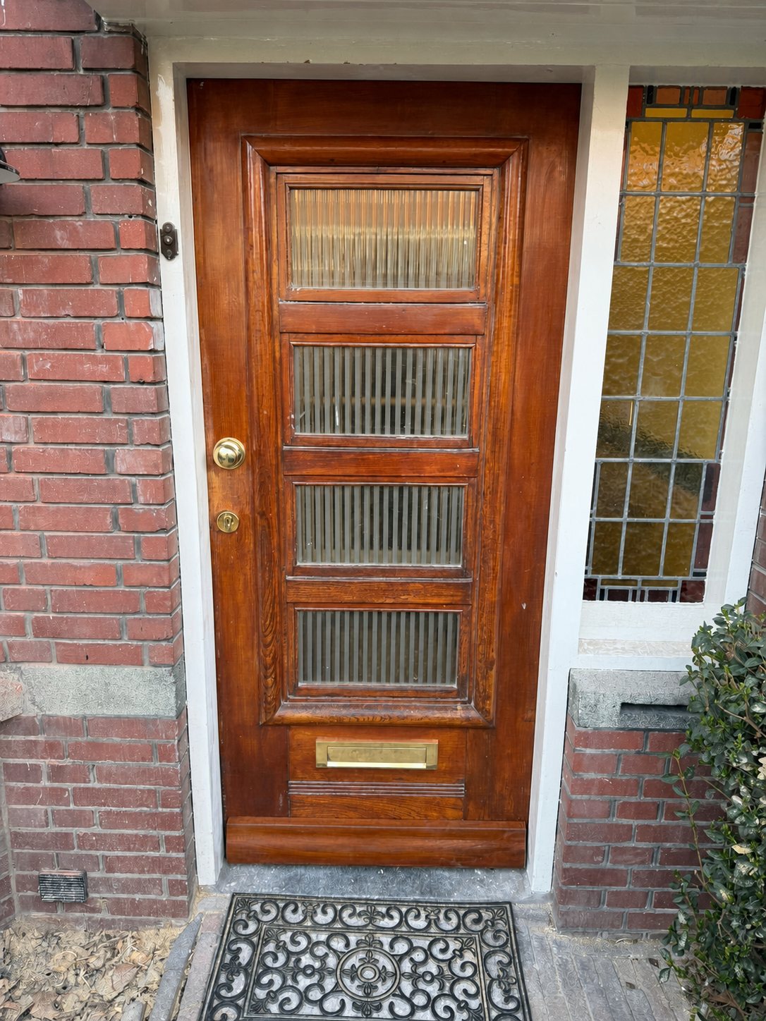 Klassieke houten voordeur met vier glasvakken en een glas-in-lood zijlicht